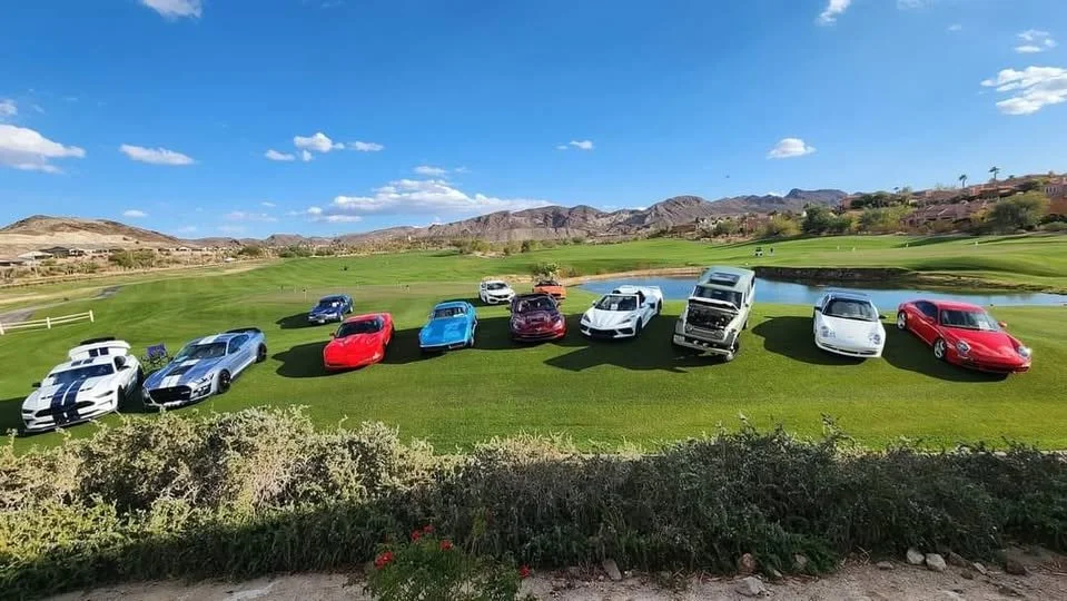 Lake Las Vegas Sport Club car show - luxury sports cars parked on a golf course with mountains in the background under a blue sky.