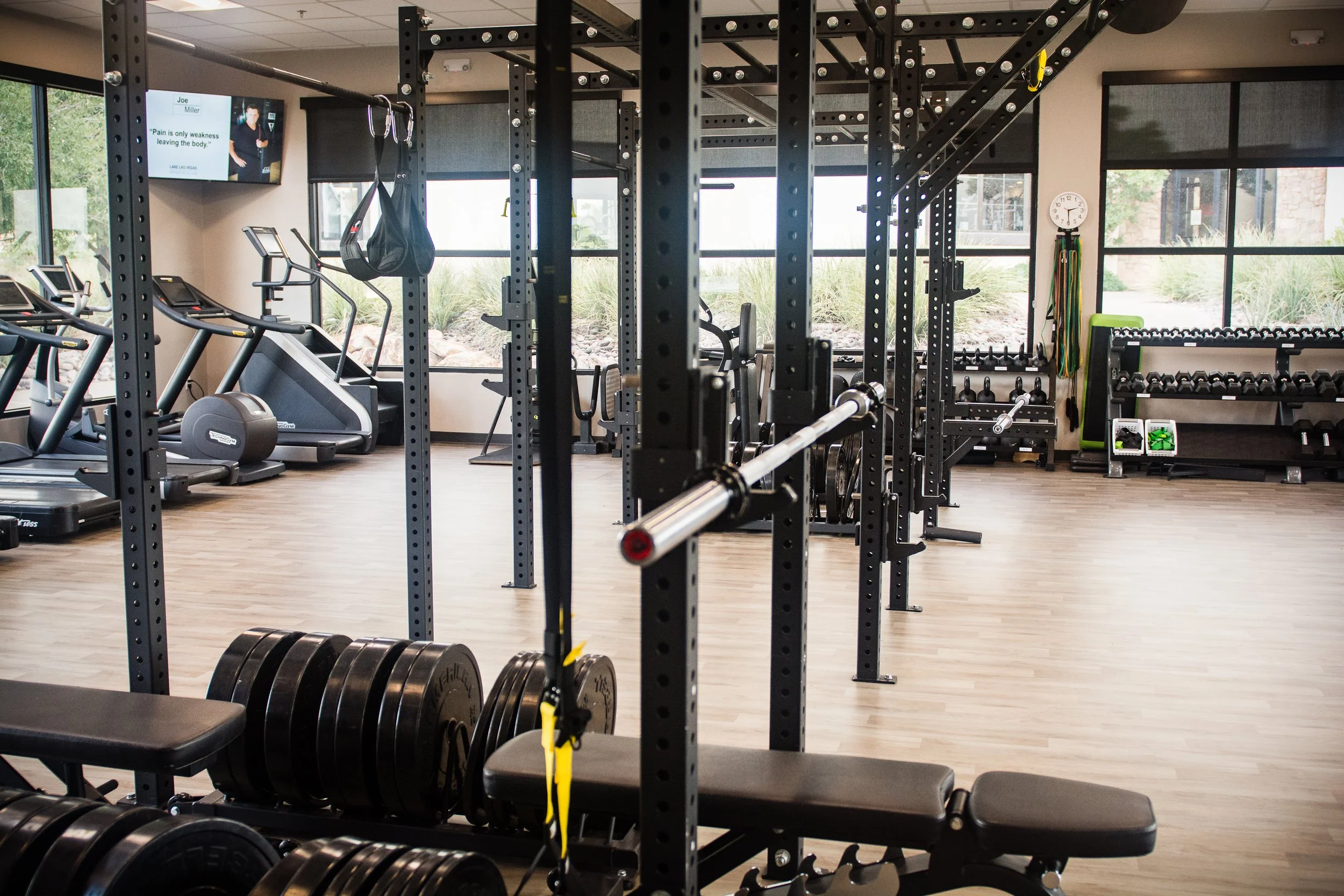 Lake Las Vegas Sport Club Performance gym with weight racks, dumbbells, kettlebells, medicine balls, resistance bands, and a bench, treadmills.