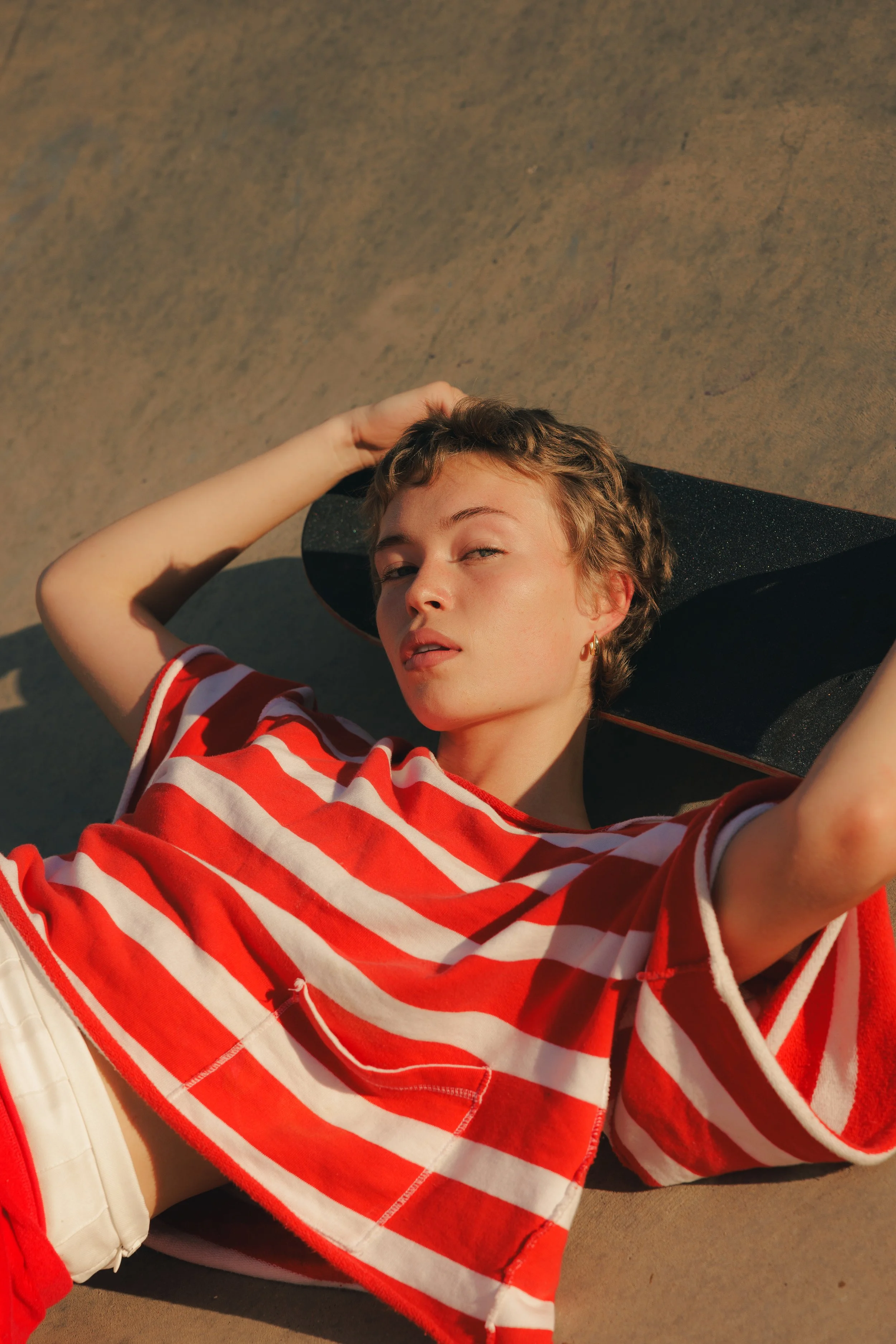 A closeup image of a woman's face with blonde hair laying on a skateboard