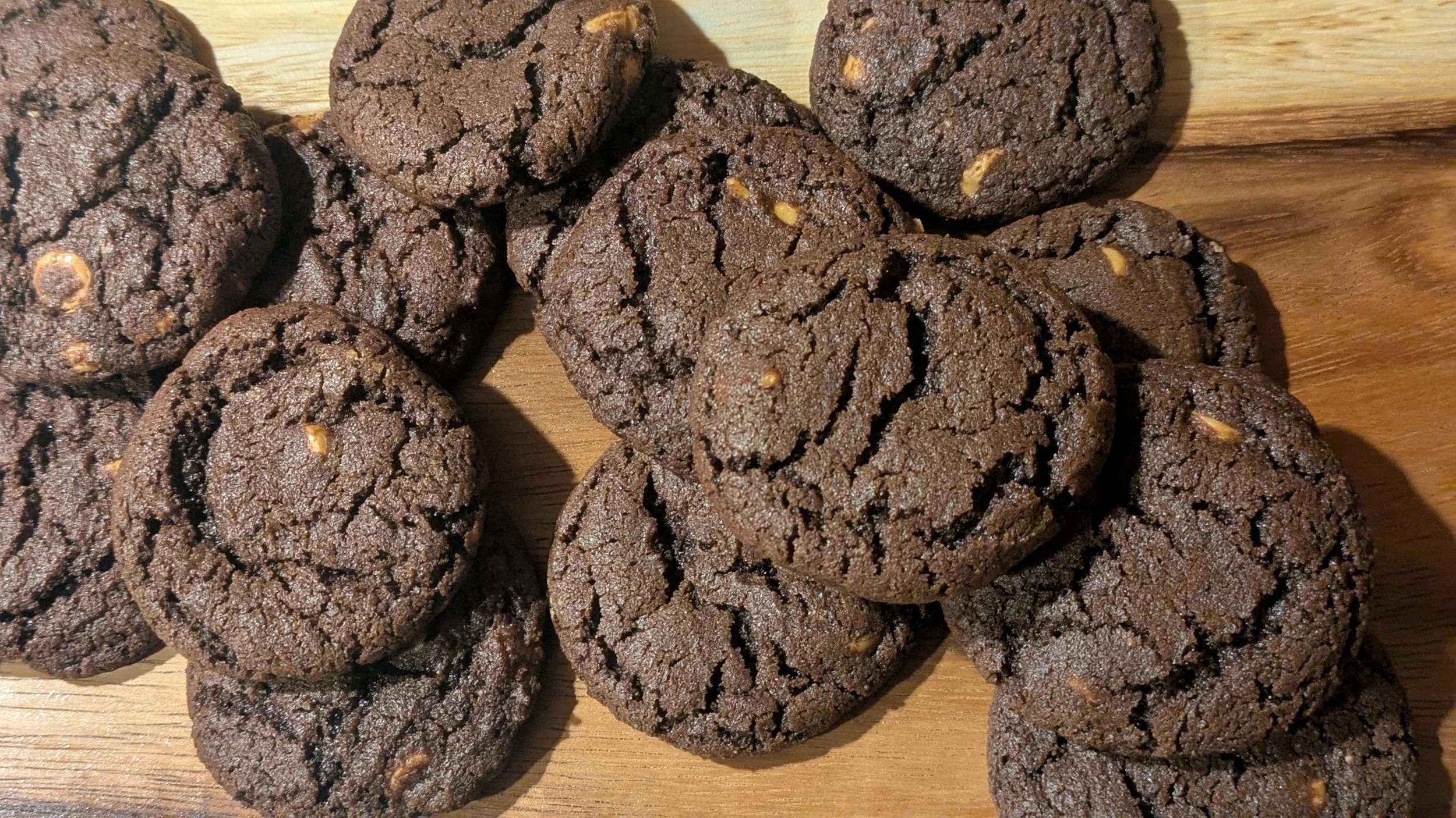 Close-up of several chocolate cookies with visible nuts on a wooden surface.