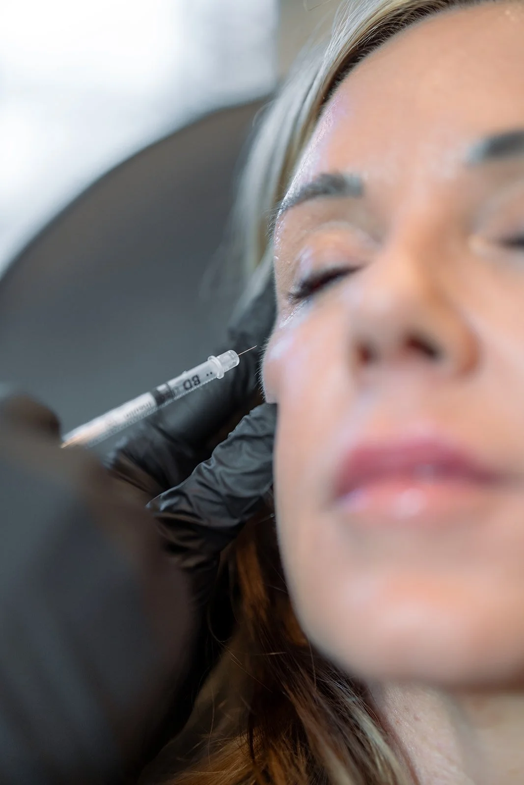 A woman getting medical botox injected into her cheek.