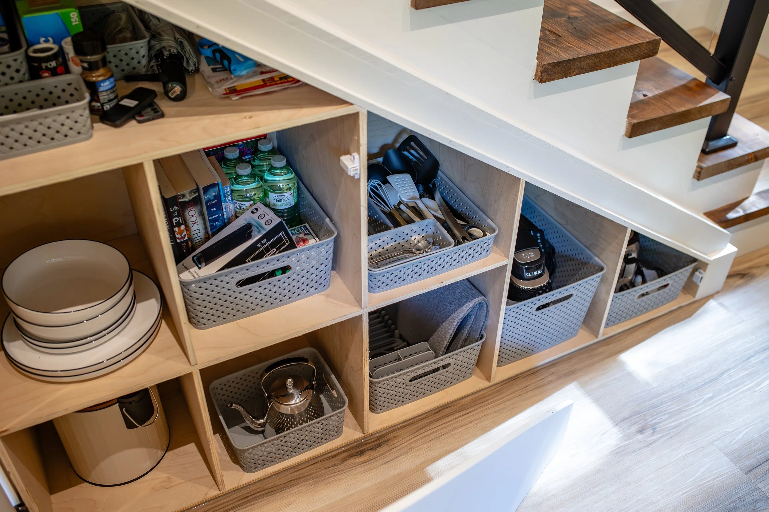 Coffee maker, kettle, toaster, dishes, utensils, and more stored under the stairs
