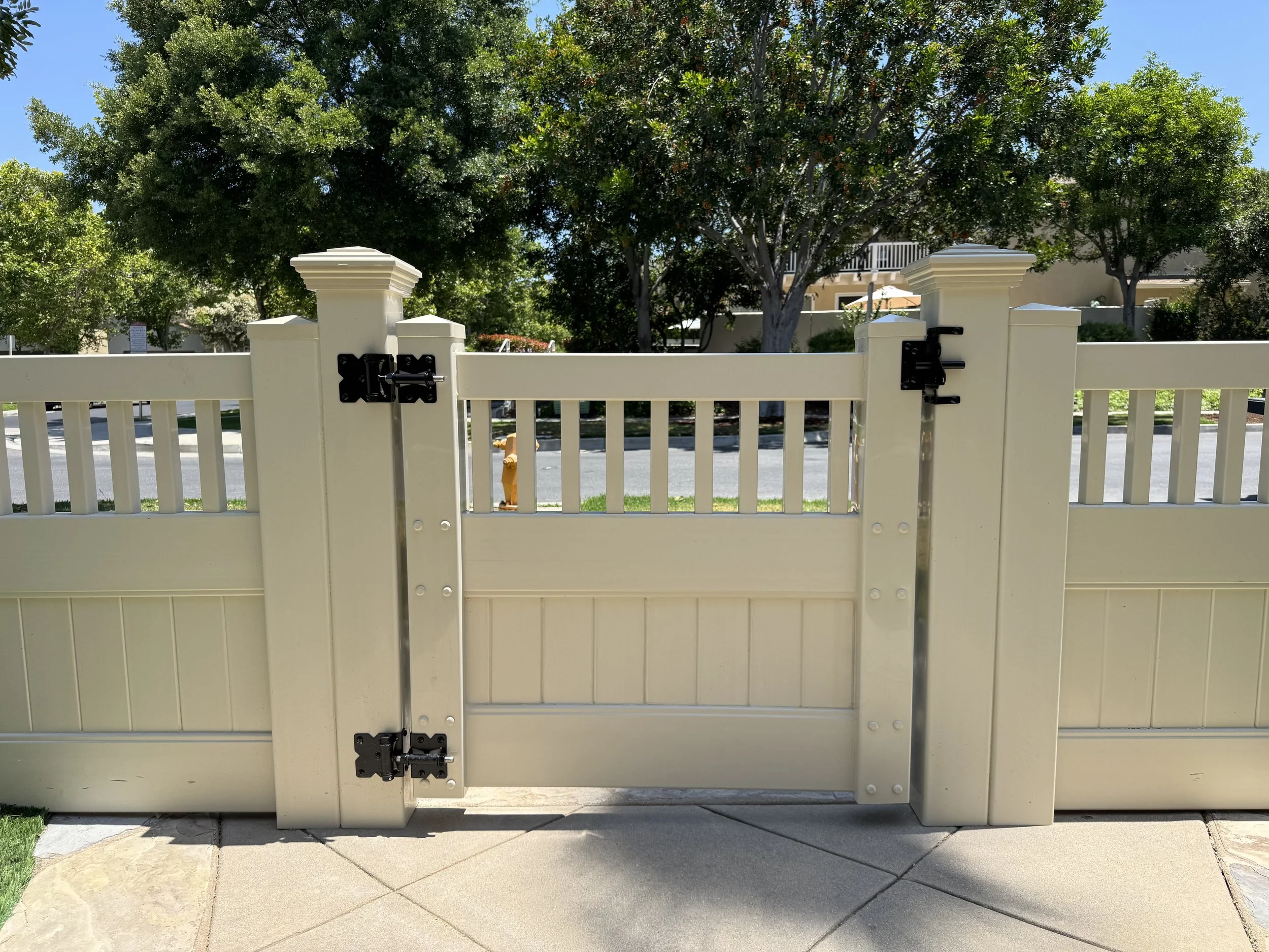Lake Forest beige vinyl gate with black hinges and latch, featuring decorative open-top slats and sturdy posts, providing stylish and secure front yard access in Orange County.