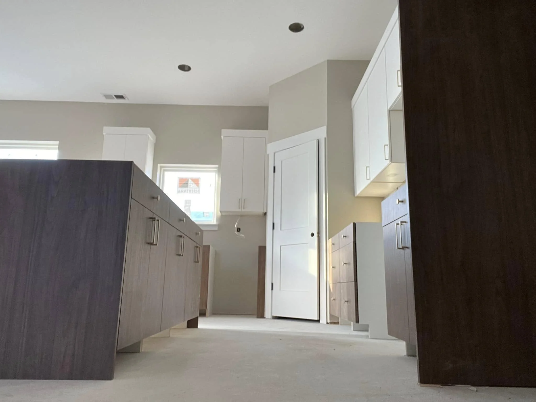 Empty modern kitchen with white cabinets, dark island, and light-colored walls, viewed from ground level.