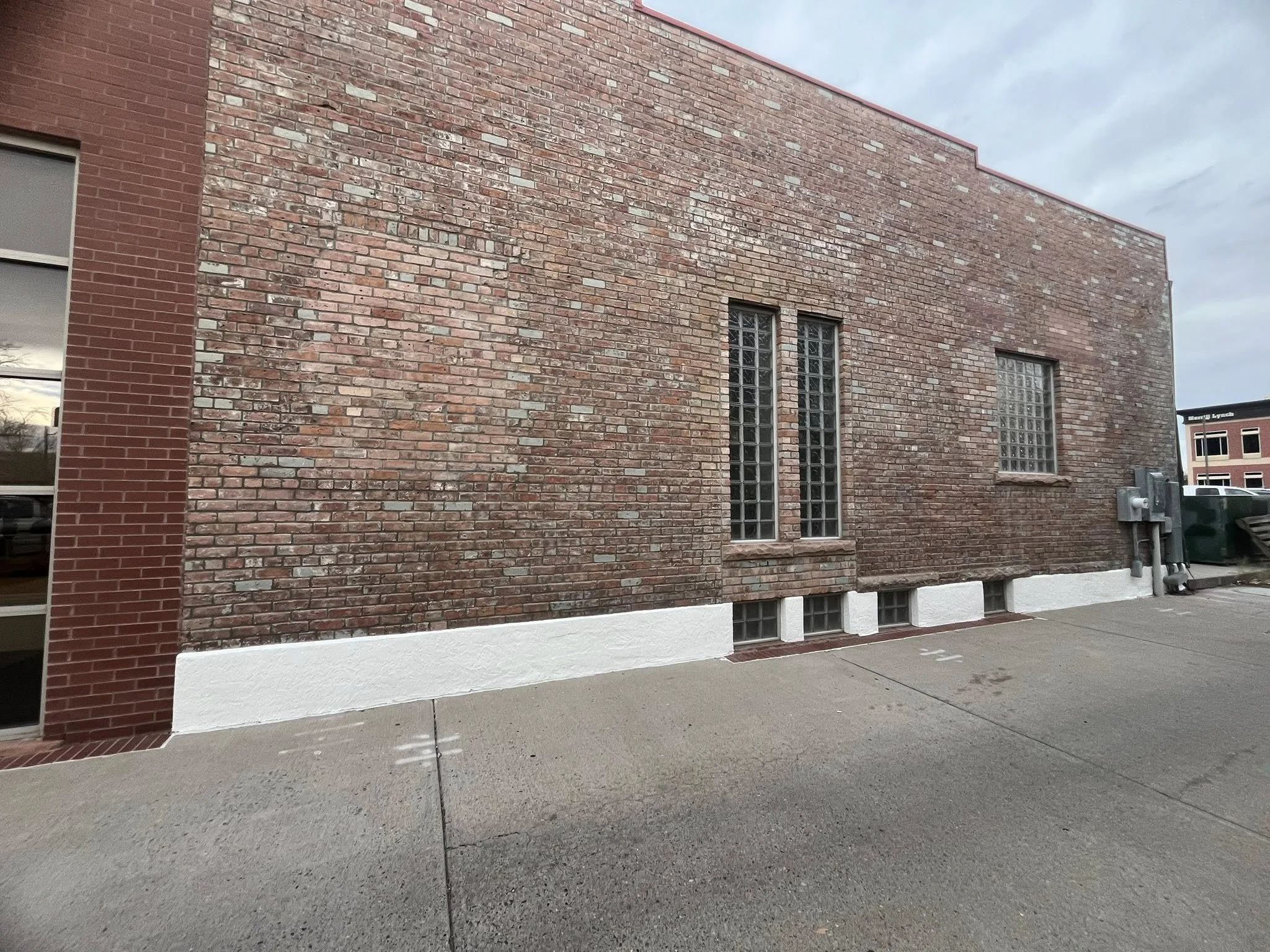 A brick building with a white painted lower wall and glass block windows.