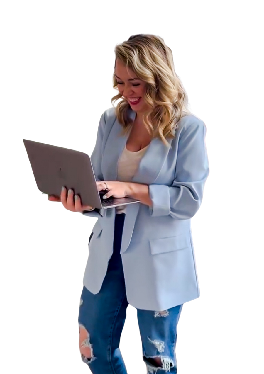 A young woman with blonde hair, wearing a light blue blazer and ripped jeans, smiling and looking at a laptop in her hands.