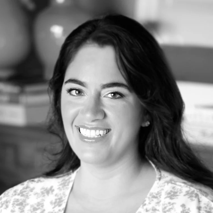 Black and white portrait of a woman smiling in a professional setting.