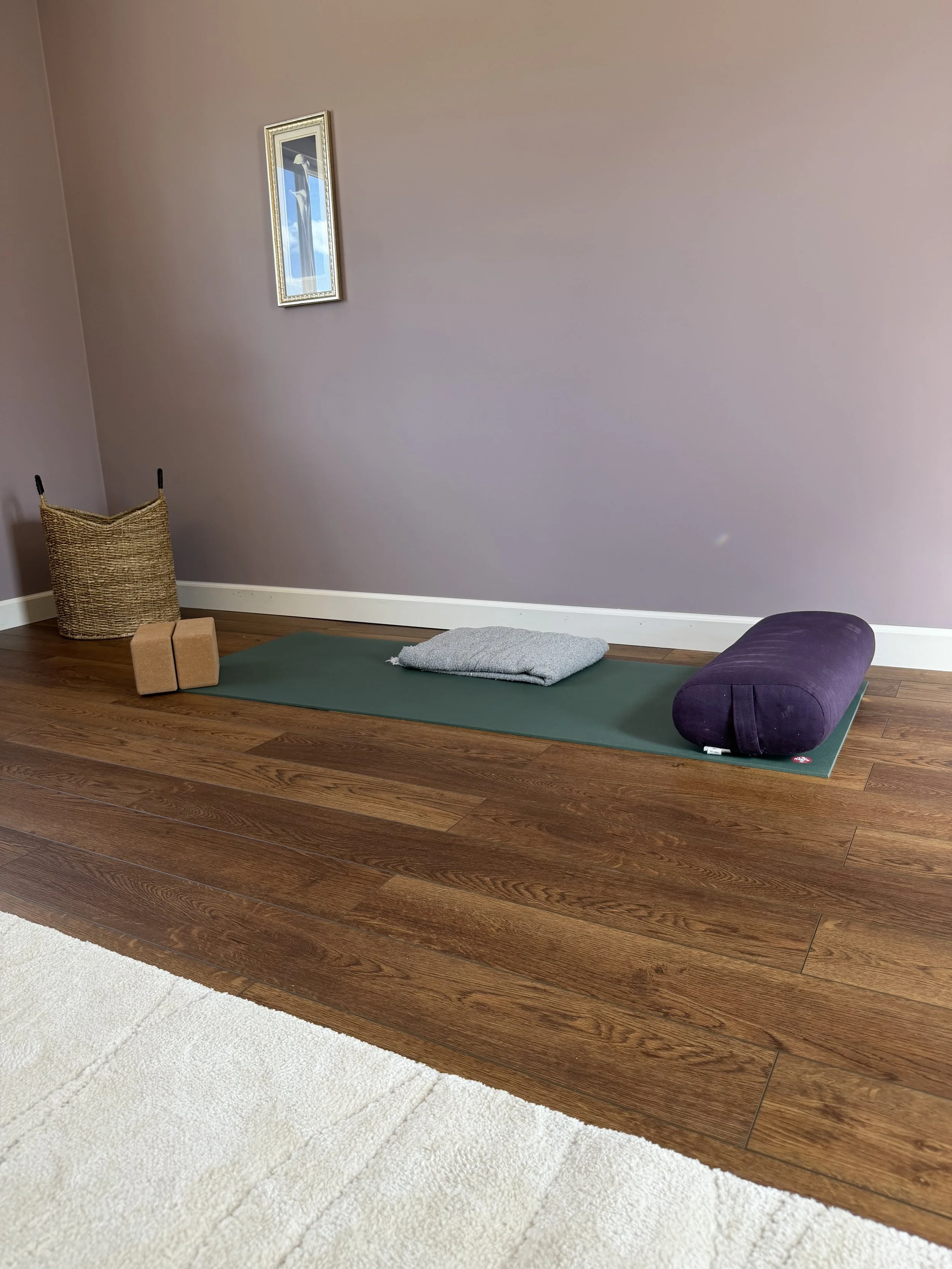 Yoga mat, bolster, blanket, and blocks arranged for a virtual trauma-sensitive yoga session.