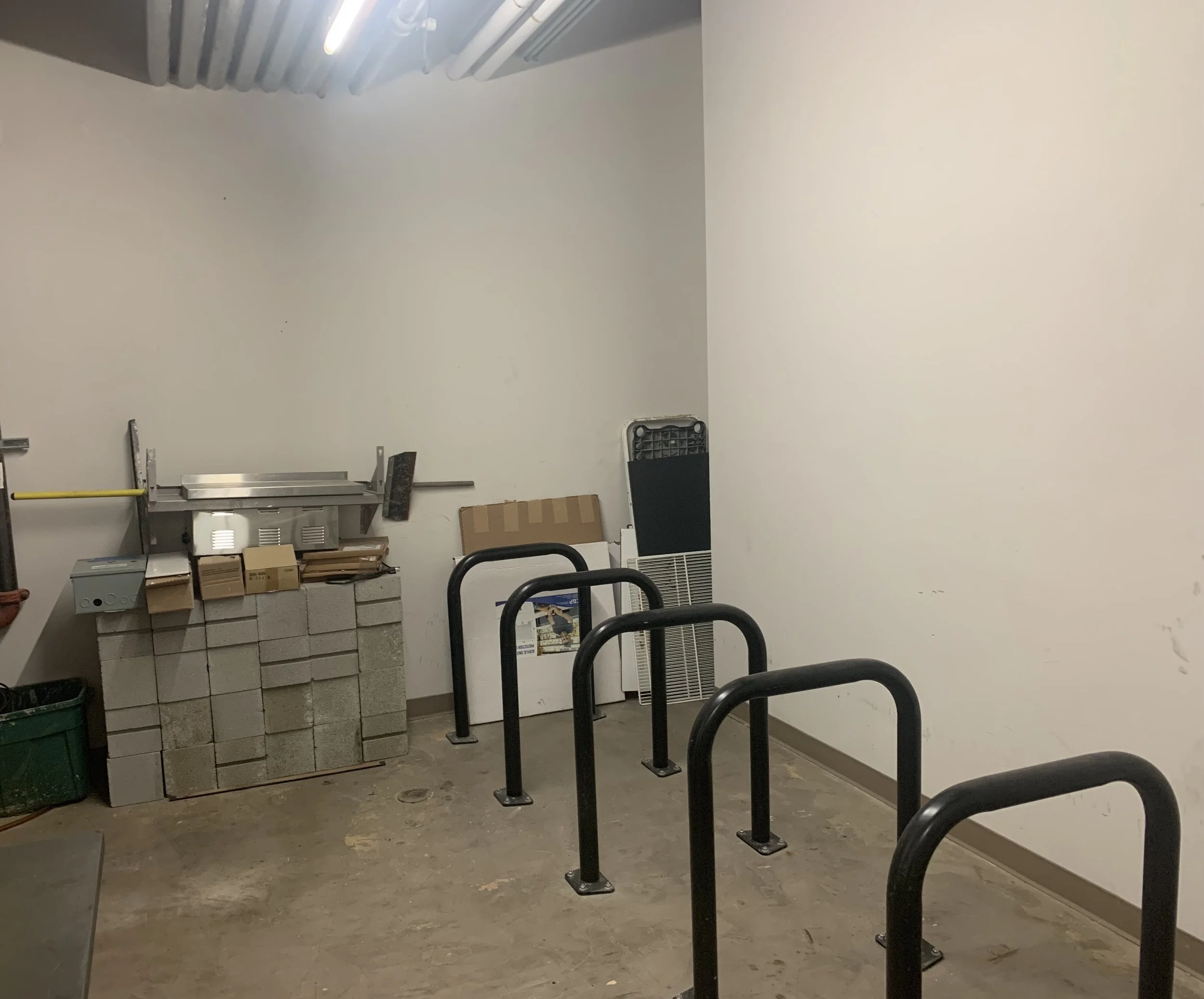  Warfield Commons basement bike storage room with five black bike racks attached to the floor. 