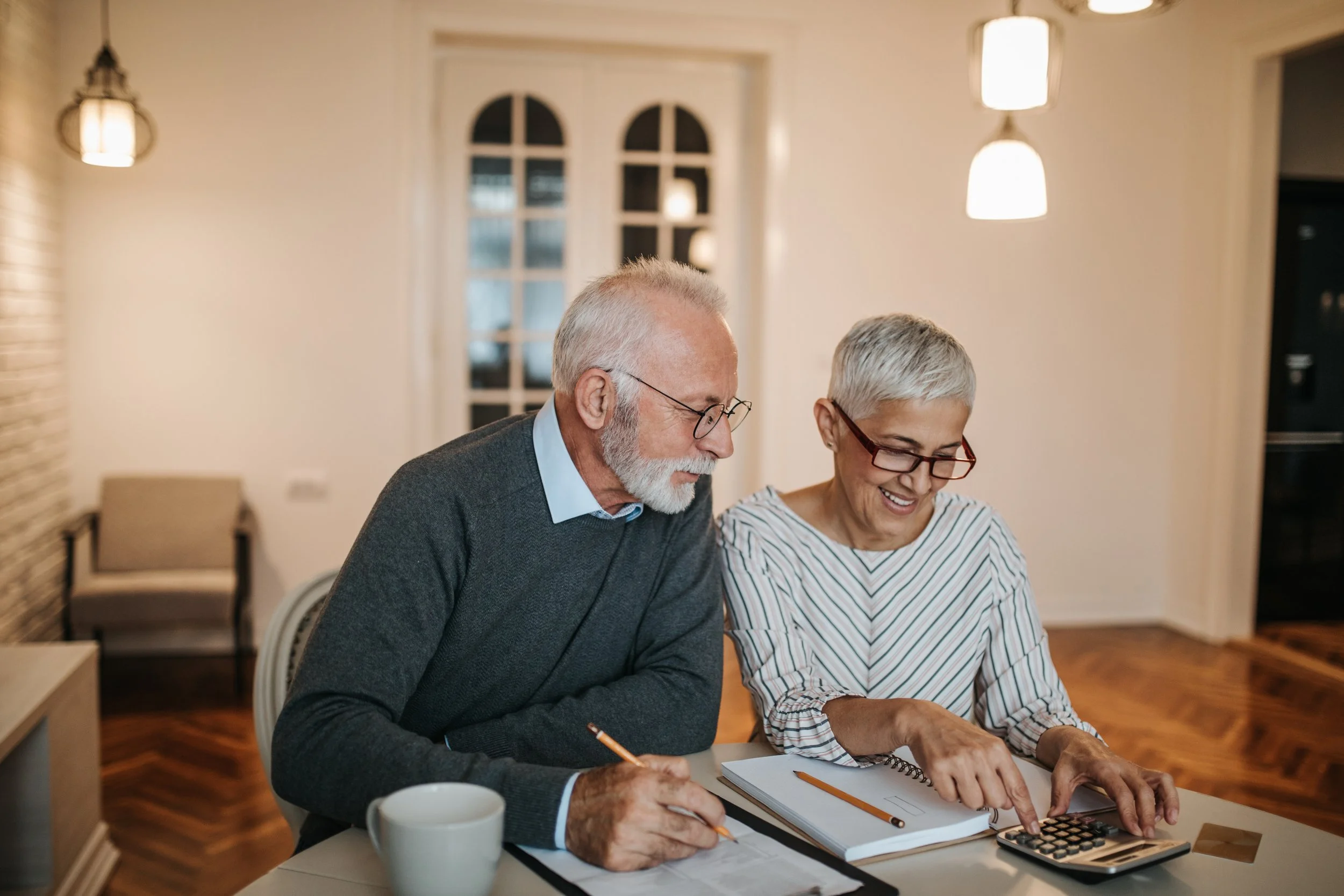 A retired couple smiling and looking over finances in their home