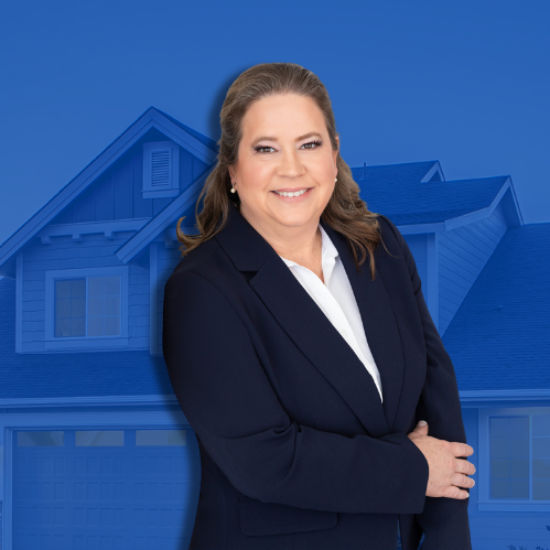 A woman in a dark suit smiling with arms crossed in front of a blue-toned background of a large house.