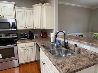 Kitchen with white cabinets, granite countertops, stainless steel oven, and a double basin sink with a black faucet.
