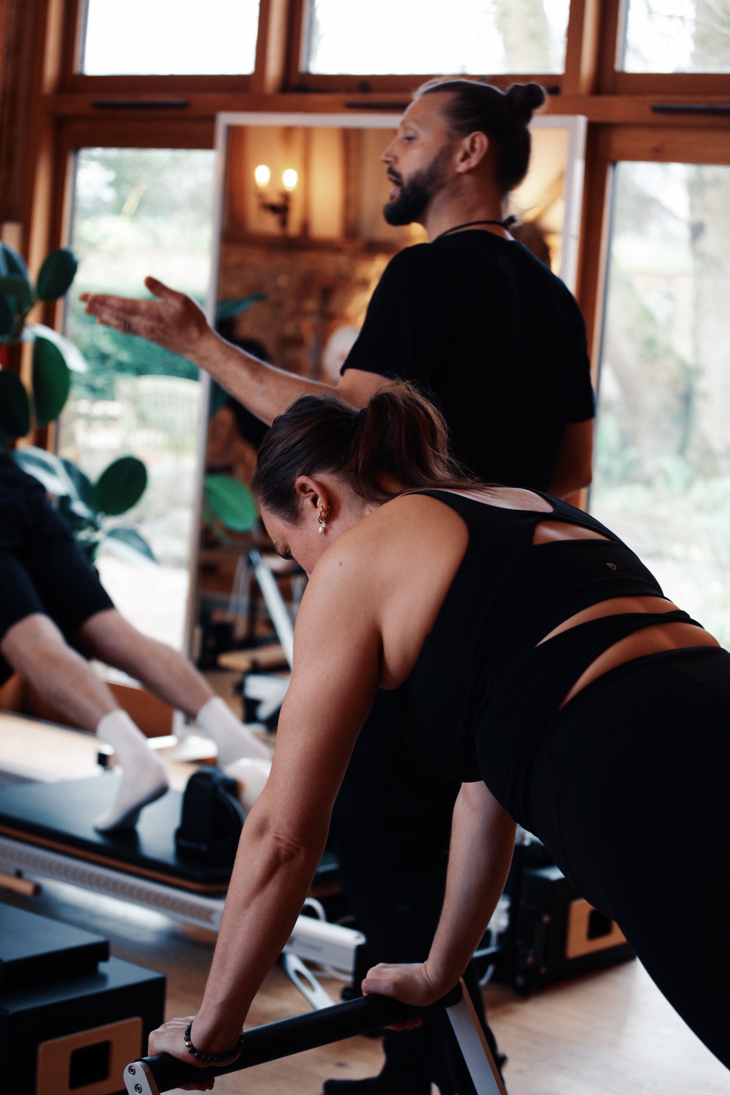 Reformer Pilates teacher trainer leading a practical instructor training session while students apply movement and teaching principles.