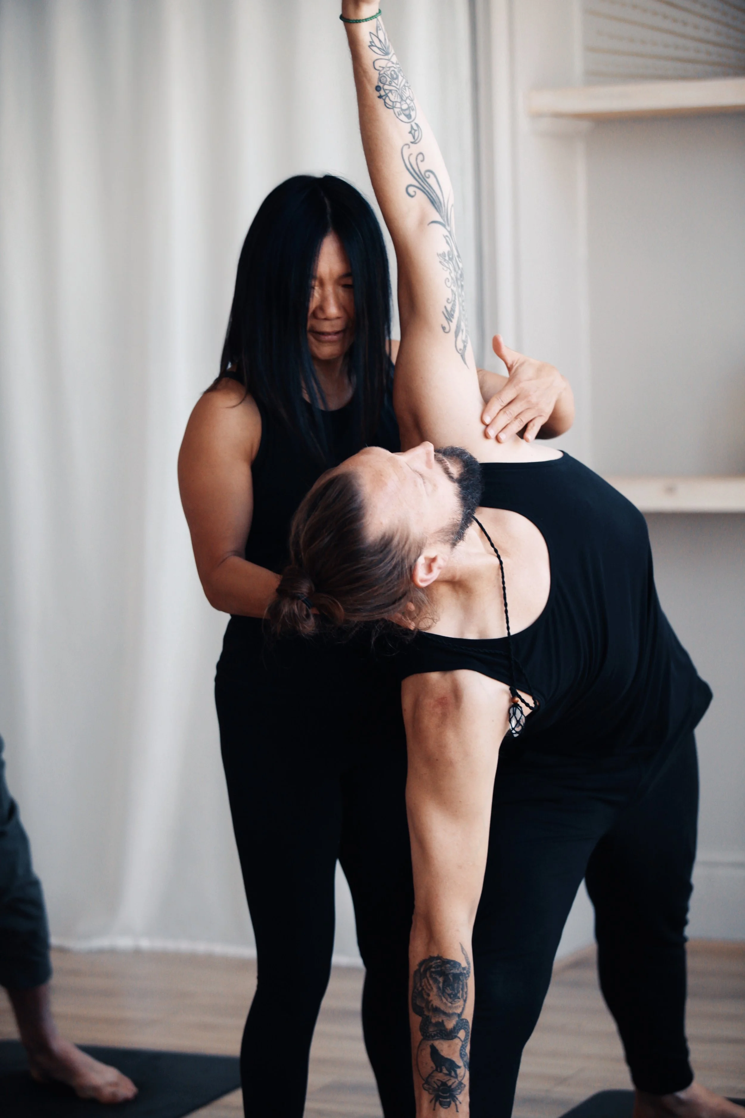 Yoga teacher trainer providing hands-on alignment guidance during intensive Vinyasa yoga teacher training.