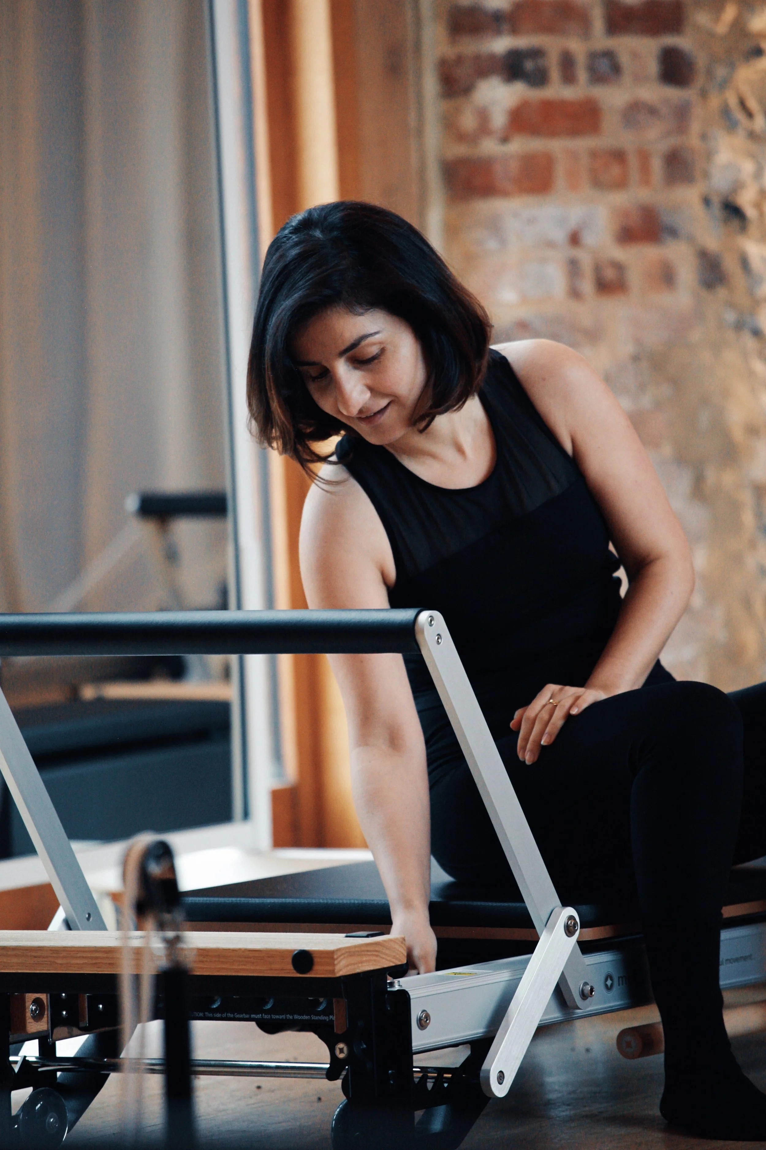 Reformer Pilates teacher trainee learning equipment setup, safety and exercise preparation during practical training.
