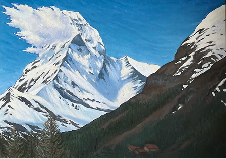 Snow-capped mountain with a steep slope, surrounded by forested hills and a clear blue sky.