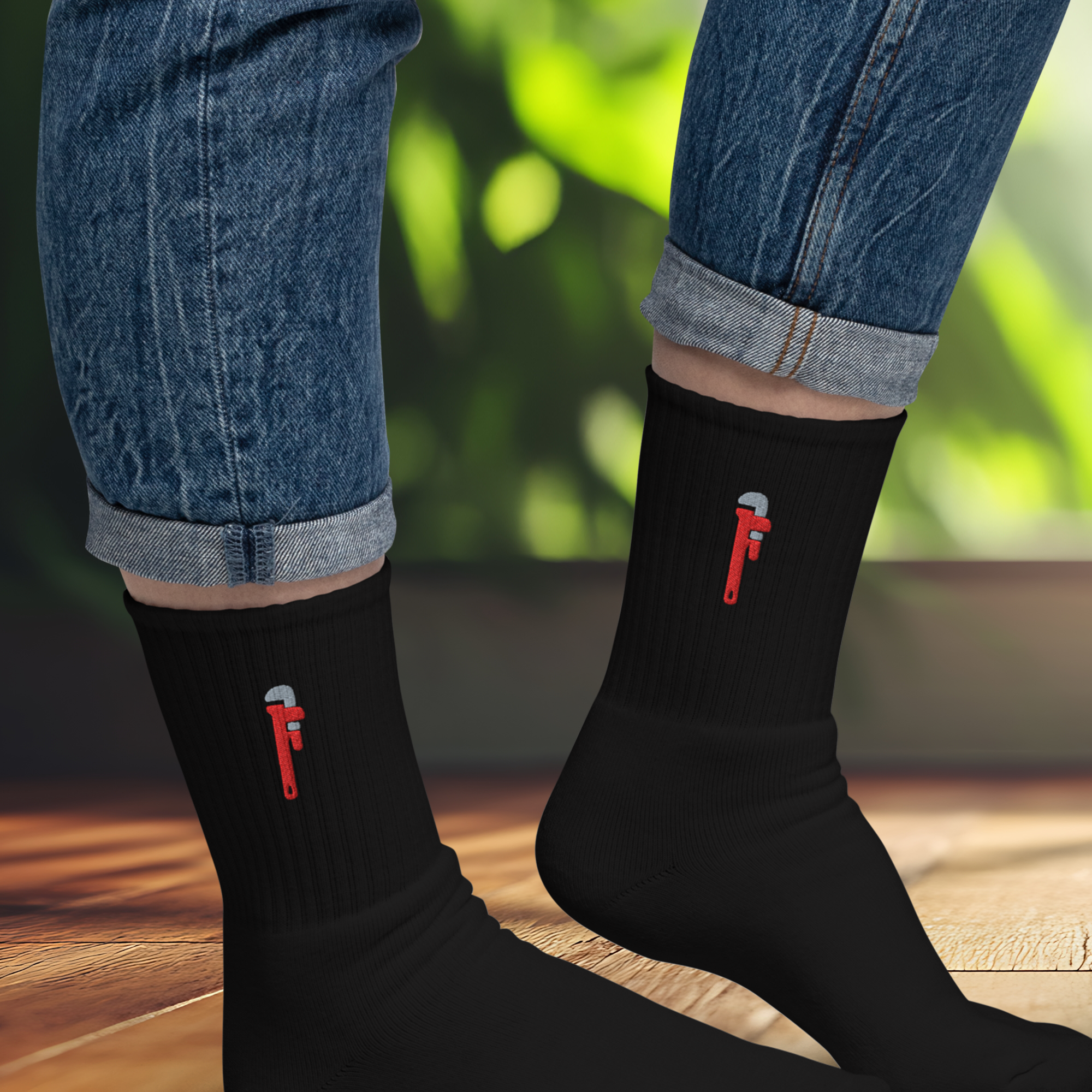 Person wearing rolled-up blue jeans and black socks with a small red and gray axe logo.
