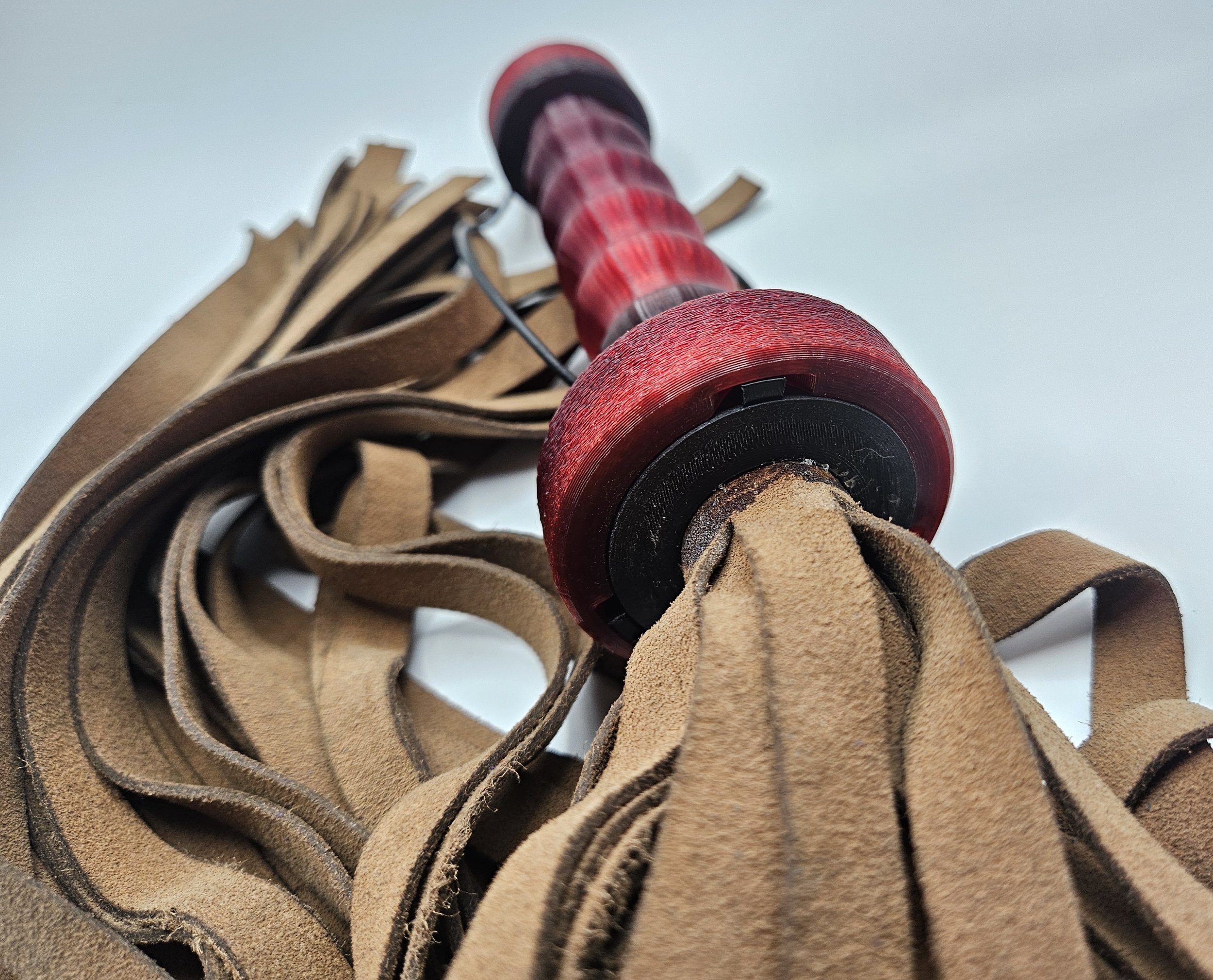 Close-up of a red and black wooden spinning top resting on brown leather strips.