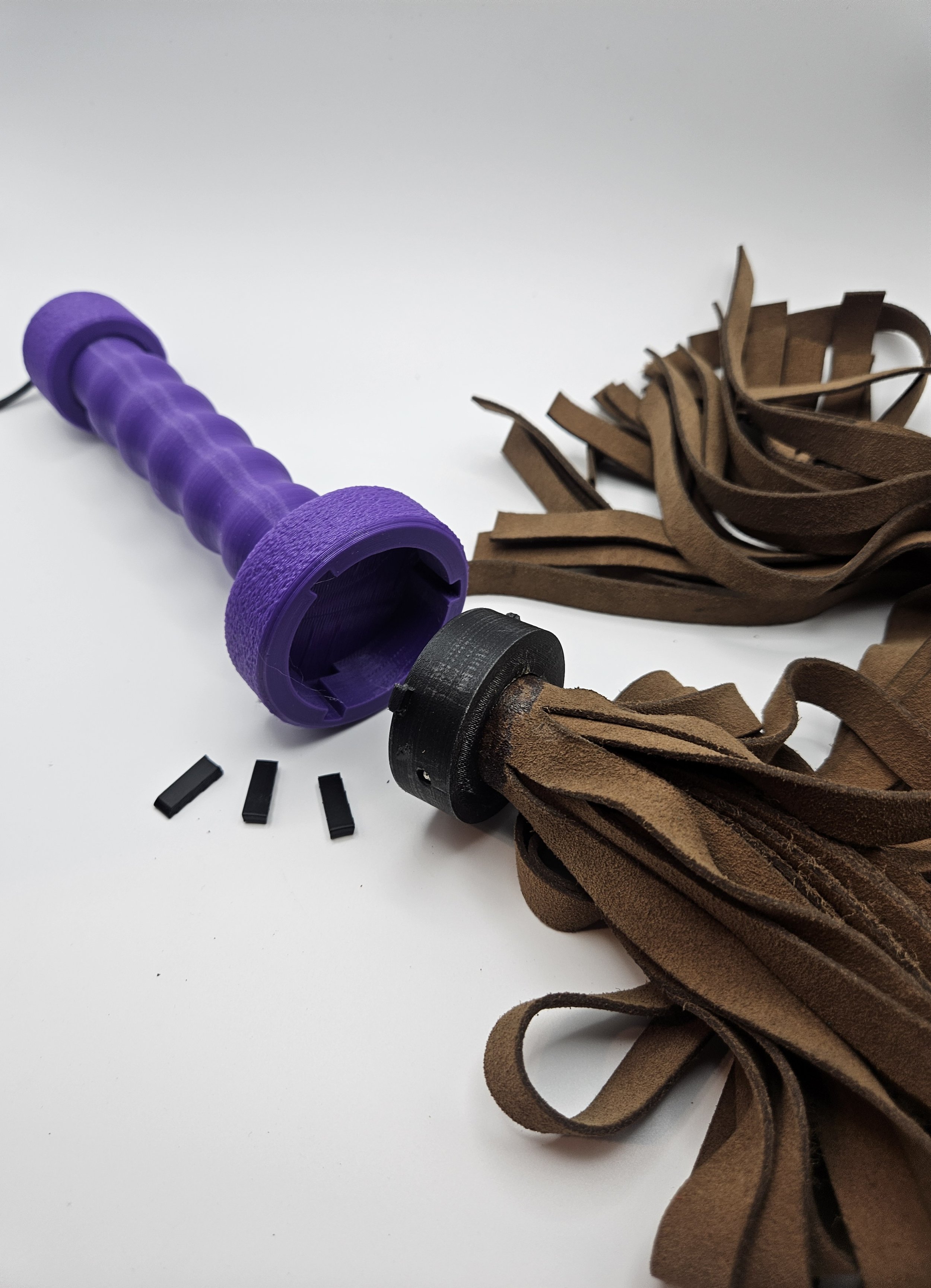 Disassembled motorcycle handlebar grip with brown leather tassels and small black plastic parts on a white background.