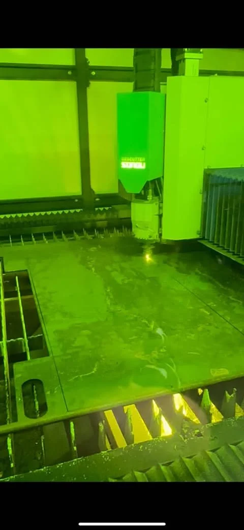 Laser cutting machine performing precision cut on metal sheet in industrial setting.