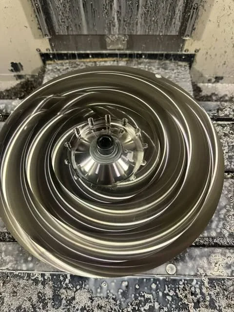 A large metal spiral component, likely a turbine or compressor part, inside a machine or manufacturing environment.