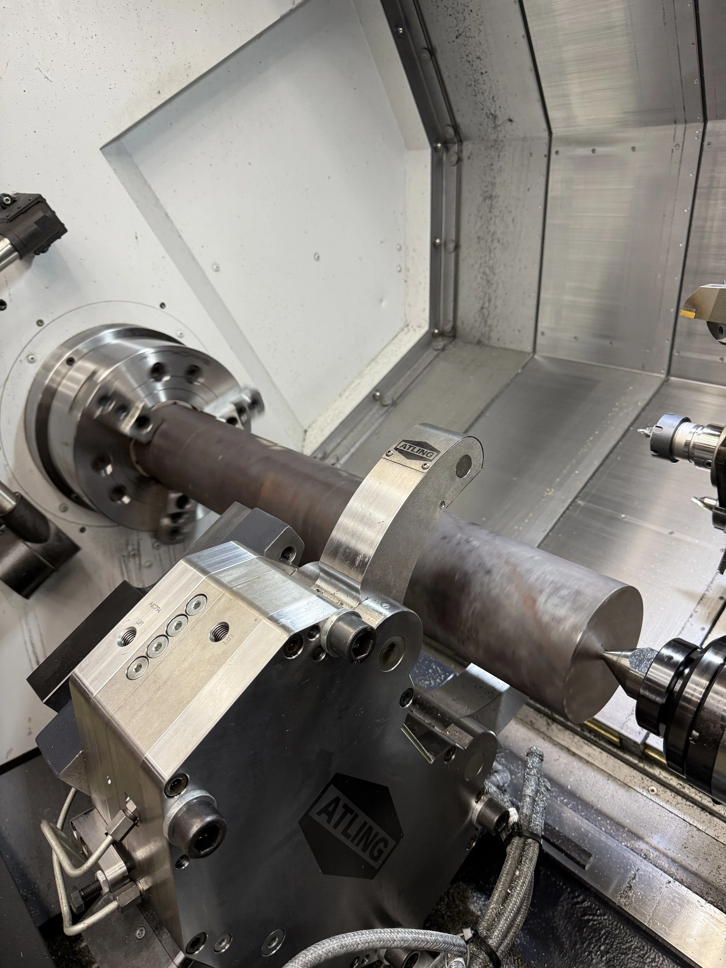 A metal lathe machine shaping a cylindrical metal workpiece during machining process.
