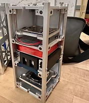 Open computer server rack with hardware components inside, placed on a wooden floor with office chairs nearby.