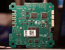 Green printed circuit board (PCB) with various electronic components and a QR code sticker.