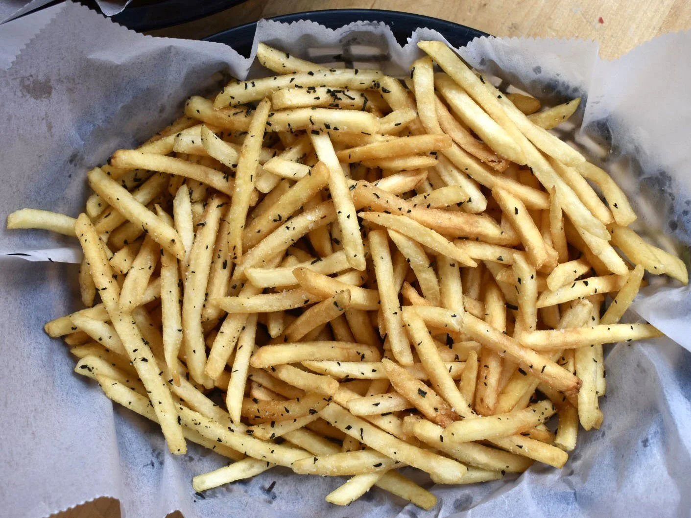 French fries sprinkled with black seasoning on parchment paper