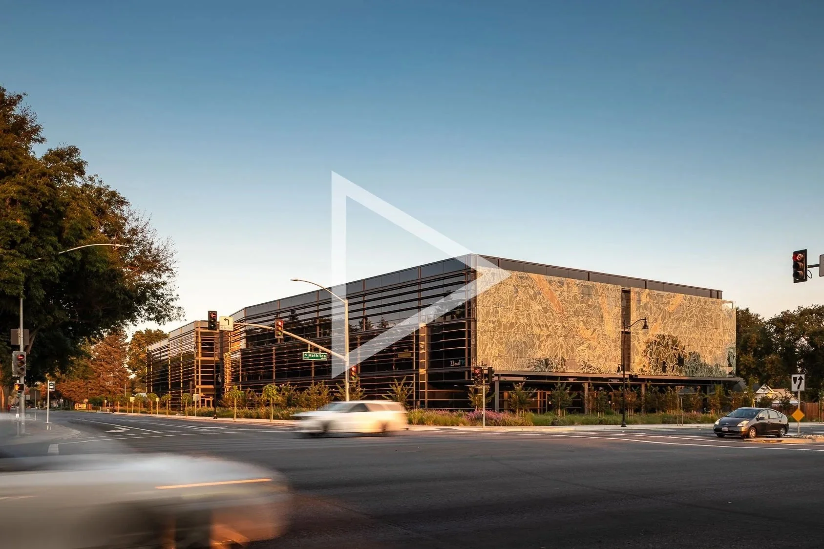 office building with car traffic in foreground, video play icon overlay