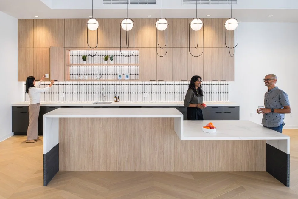 modern office kitchen with three people, light wood, dark gray and white finishes