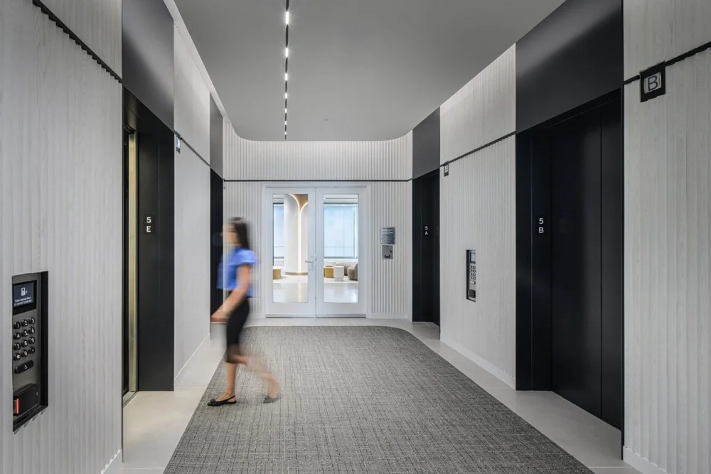 modern elevator lobby with white wood paneling, woman walking