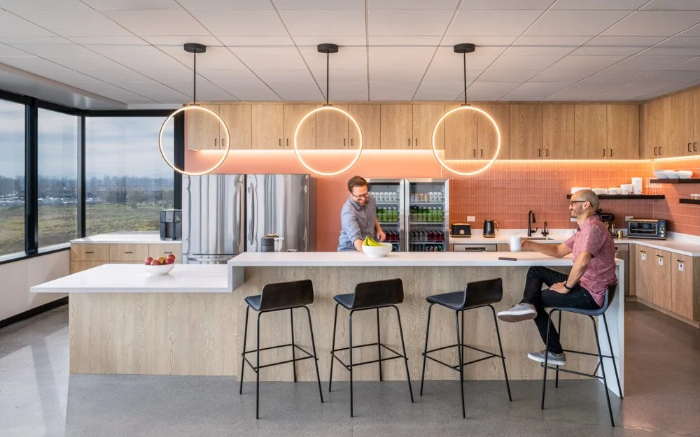 two men in an office kitchen, circular light fixtures and salmon colored tiles