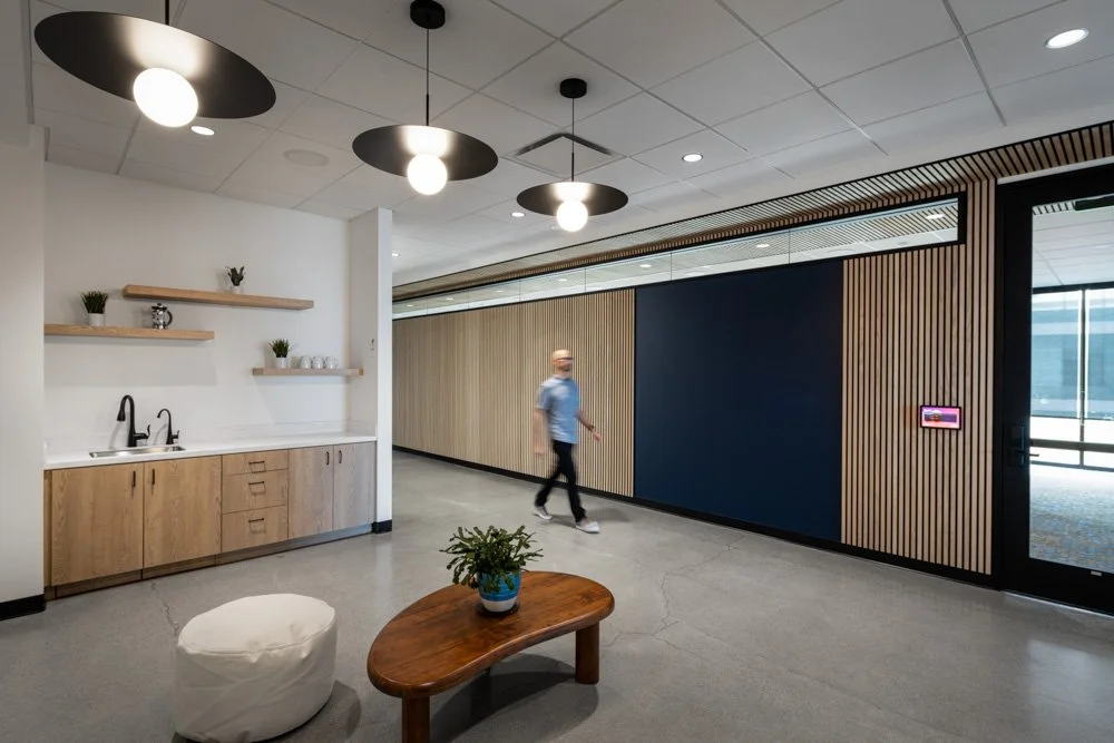 man walking in a modern office lobby with dark wood accents