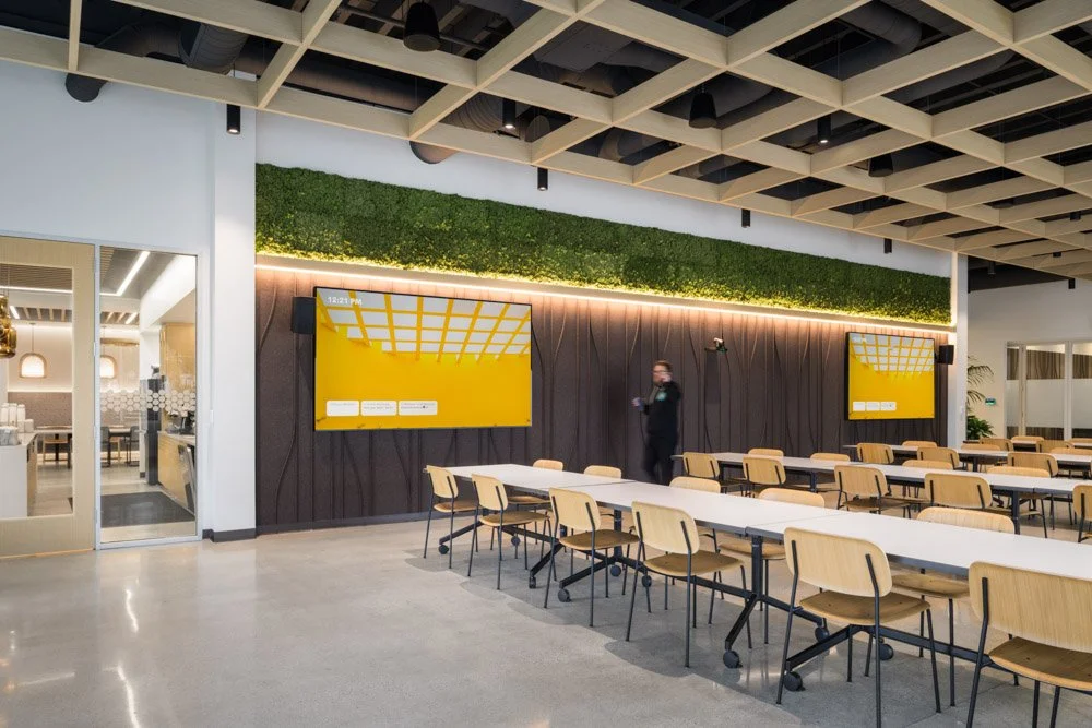 modern break / dining area in an office with felt acoustical wall covering and two large TV monitors