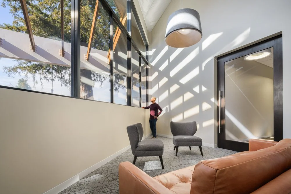 triangular room with large window, man standing, and sunlight