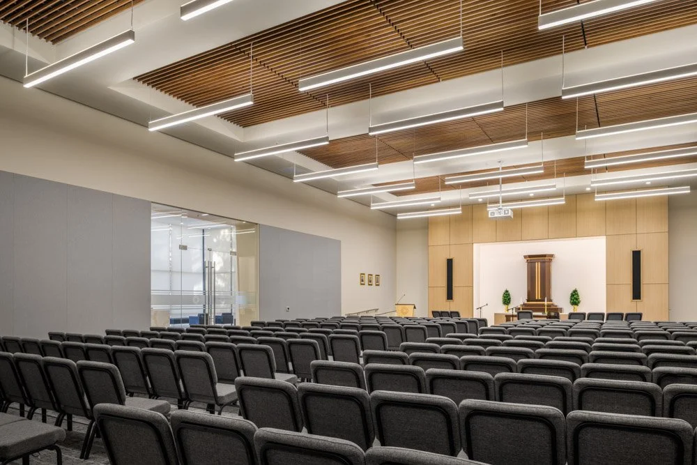 main sanctuary space with rows of gray chairs, wood ceiling, and pulpit