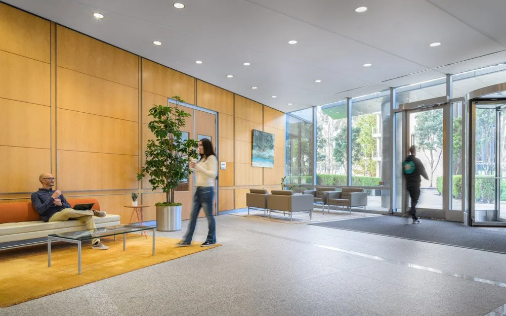 office lobby with mid century modern styling and warm wood wall panels, three people