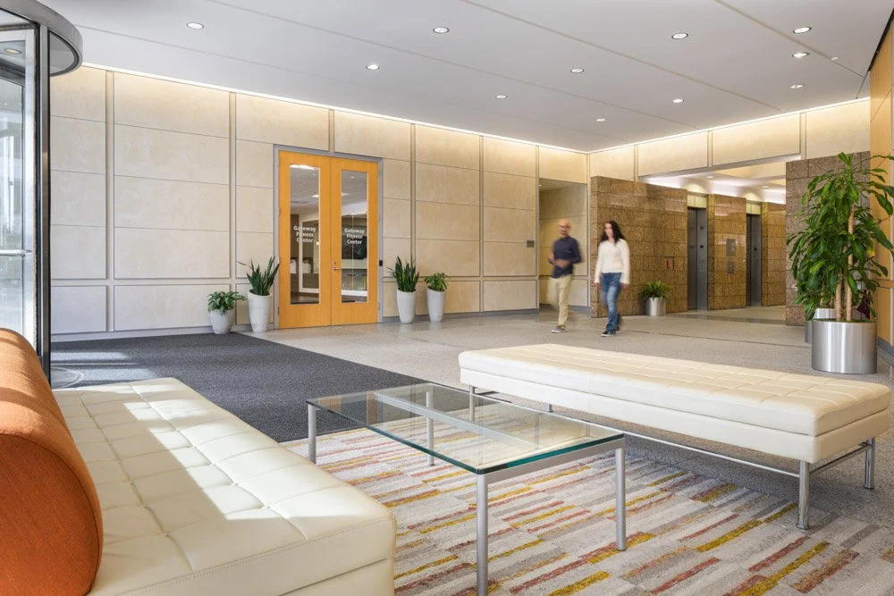 modern office loby with cream colored lounge furniture, man and woman walking