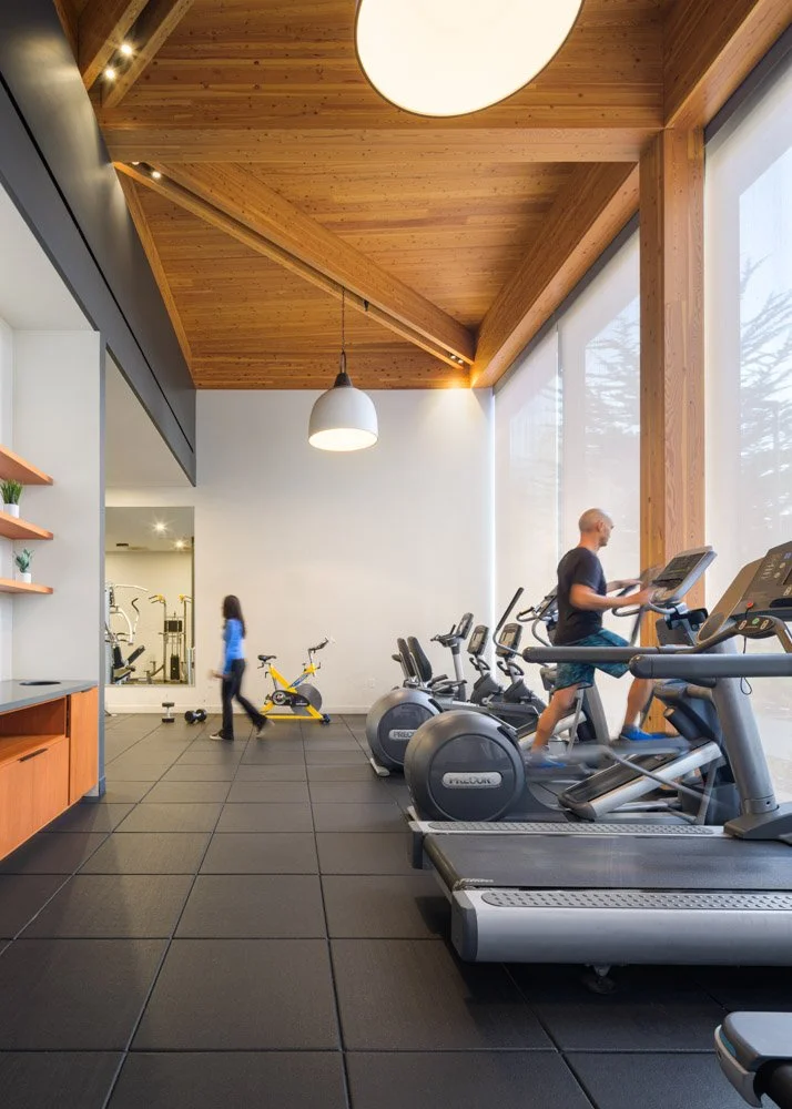 gym space with two people, warm wood ceiling, large pendant lights