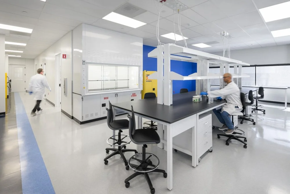 lab space with two workers, fume hood, blue accents