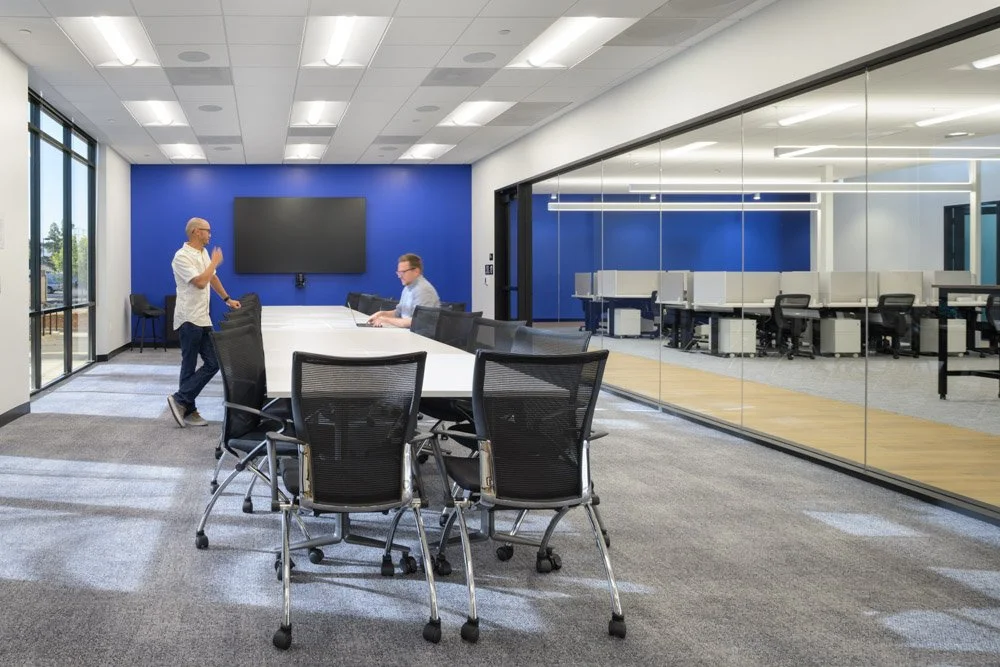 all hands room with conference table, two men, glass partition