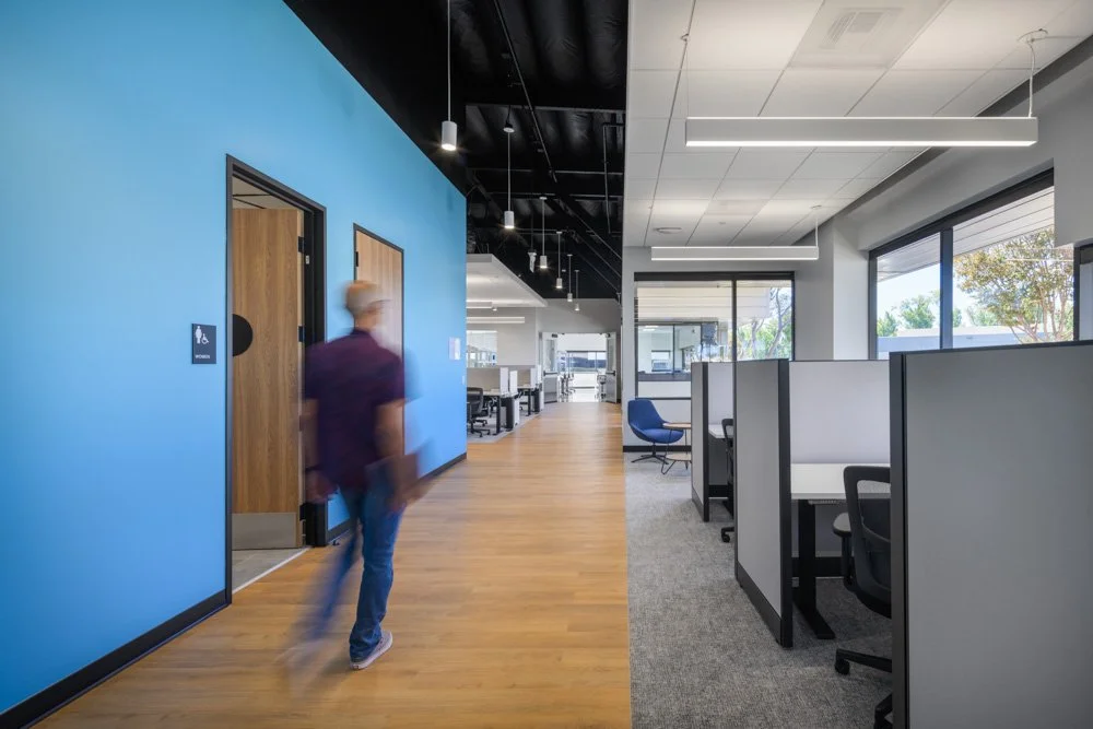office cubicles and walkway, light blue accent wall, man walking
