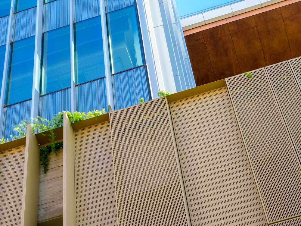 detail image of bronze colored perforated panels, glazing, and wood soffit
