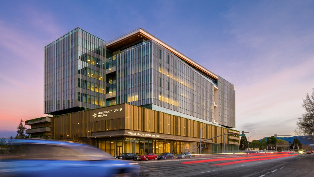 mid rise office building at dusk with blue car passing by