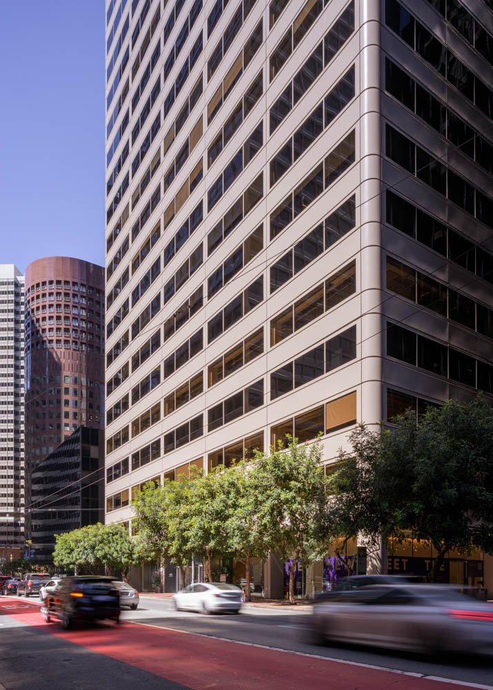 cars with motion blur passing in front of a highrise office building