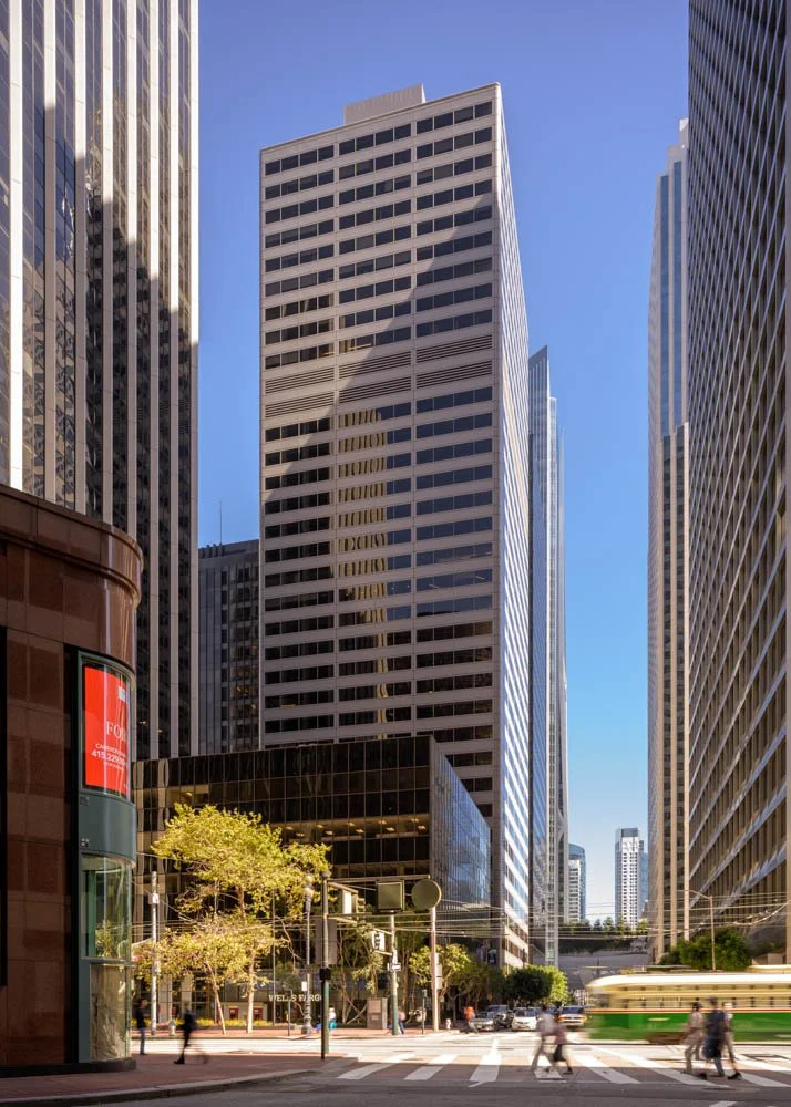 highrise office building with pedestrians and trolley car passing in the foreground