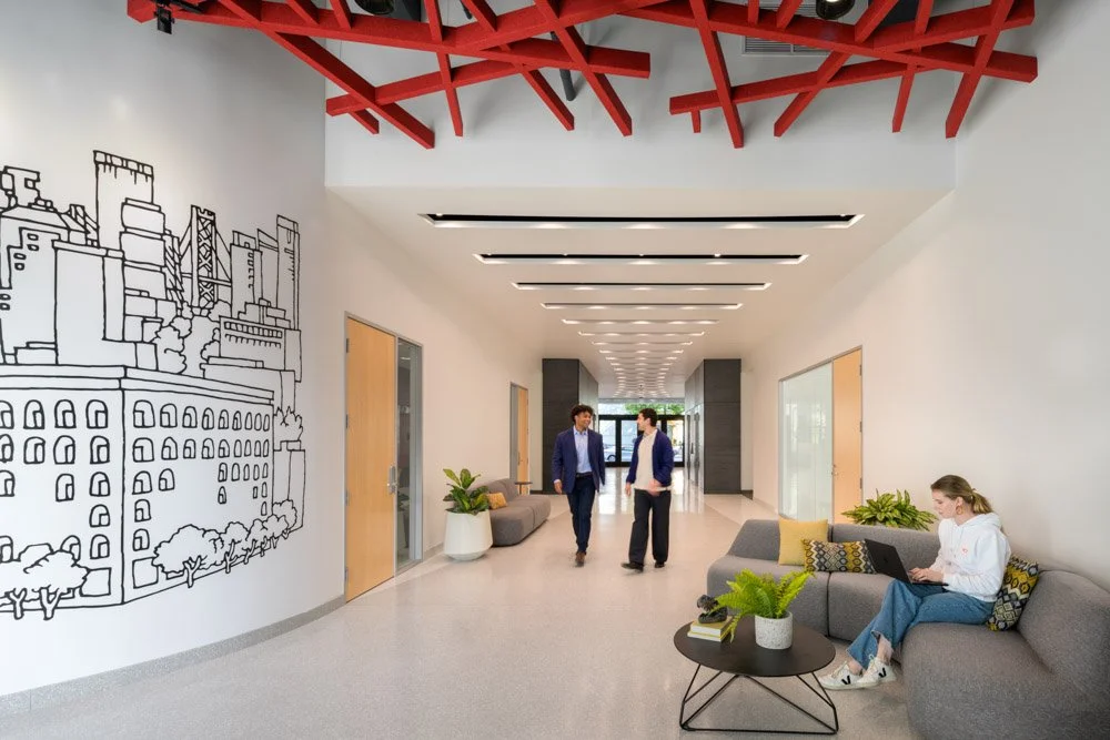 modern office lobby with mural and three workers, red ceiling