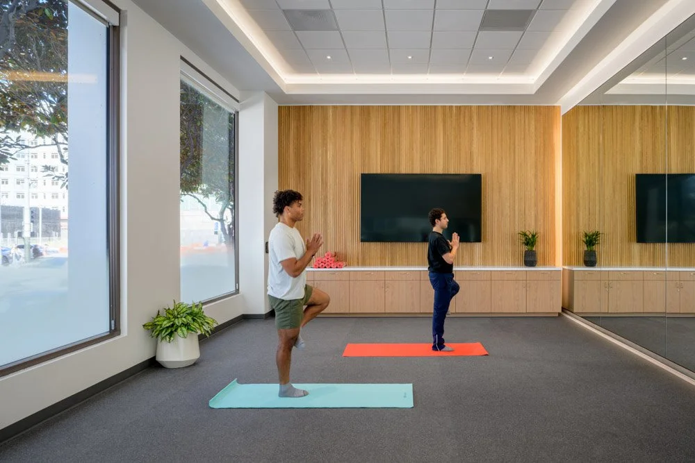 two men doing yoga in a modern yoga studio with ribbed wood wall covering