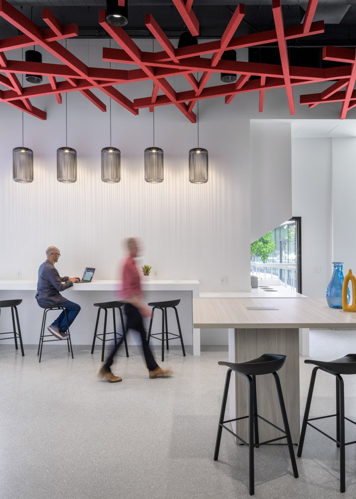 modern office break area with bar seating, black wire light fixtures, two men, red ceiling